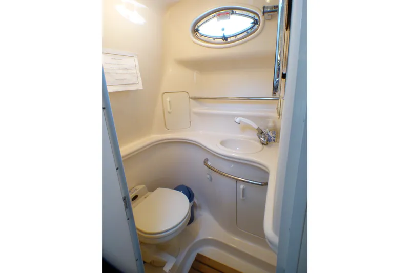 Slide: The Image of 2002 Sea Ray 340 Sundancer bathroom with toilet, sink, and porthole window. - 11