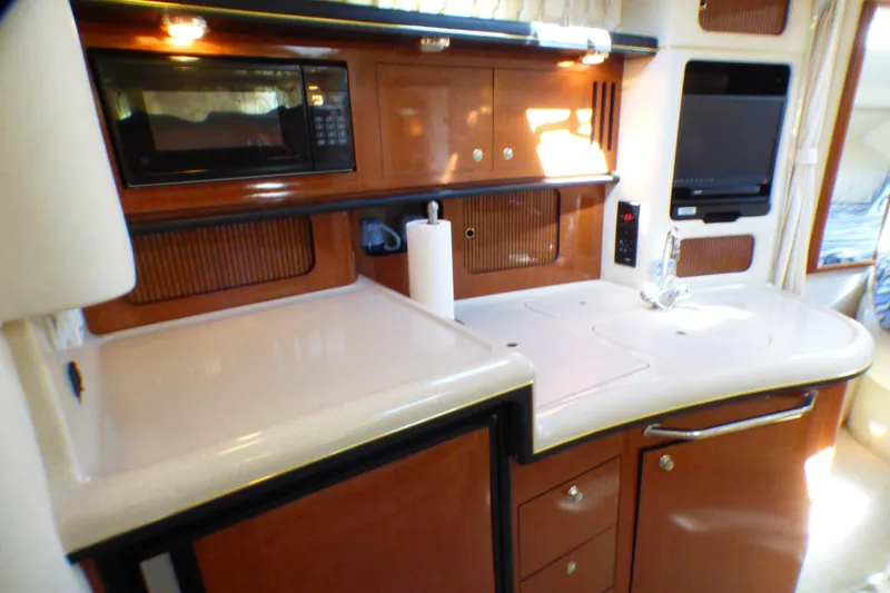 Slide: The Image of 2002 Sea Ray 340 Sundancer yacht kitchen with microwave, sink, and wooden cabinetry. - 5