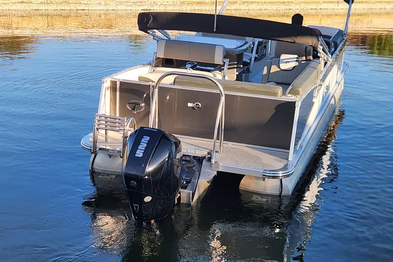 Slide: The Image of 2022 Tahoe Tritune 2585 ENT pontoon boat with Mercury outboard motor on calm water. - 10