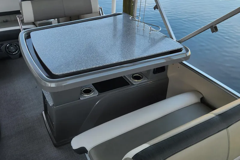 Slide: The Image of 2022 Tahoe Tritune 2585 ENT boat interior with table and seating by the water. - 17