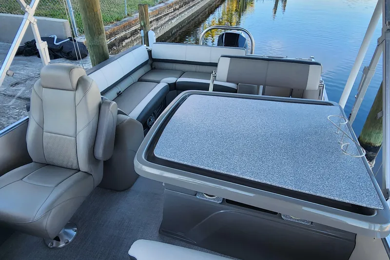 Slide: The Image of 2022 Tahoe Tritune 2585 ENT boat interior with seating and table by the water. - 18