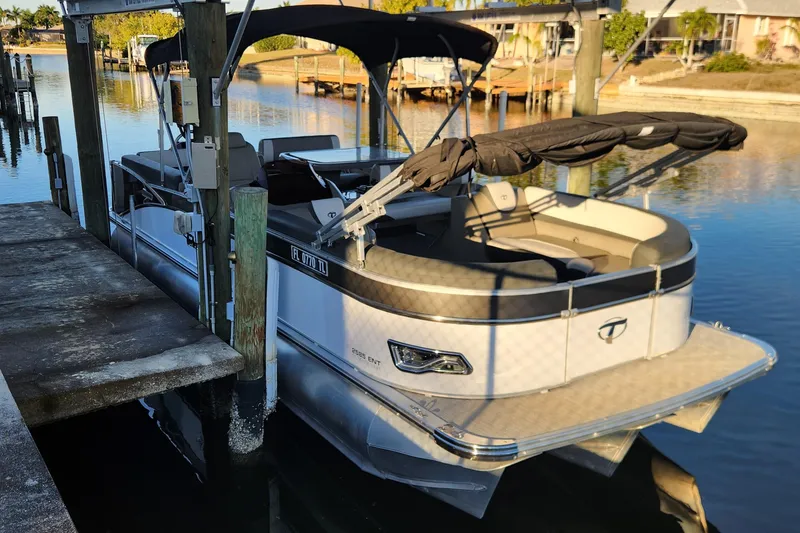 Slide: The Image of 2022 Tahoe Tritune 2585 ENT pontoon boat docked on calm water. - 25