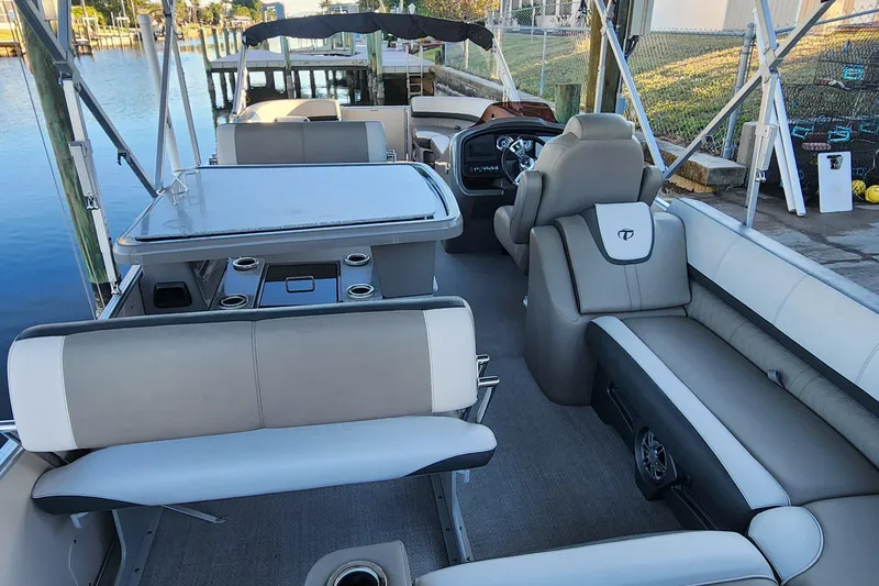 Slide: The Image of 2022 Tahoe Tritune 2585 ENT pontoon boat interior with seating and table setup. - 28
