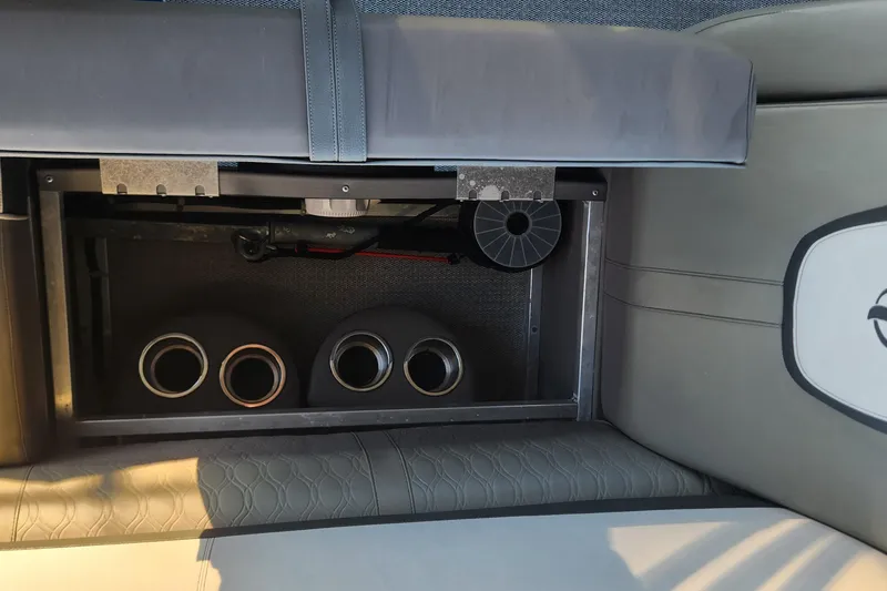 Slide: The Image of Under-seat storage compartment in 2022 Tahoe Tritune 2585 ENT boat, featuring cup holders and equipment. - 36
