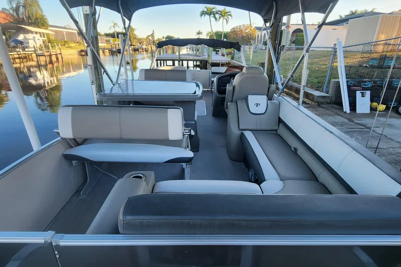 Slide: The Image of 2022 Tahoe Tritune 2585 ENT pontoon boat interior with seating and canopy, docked by a canal. - 41
