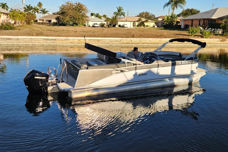 Slide: The Image of 2022 Tahoe Tritune 2585 ENT pontoon boat on calm water with Mercury outboard motor. - 7