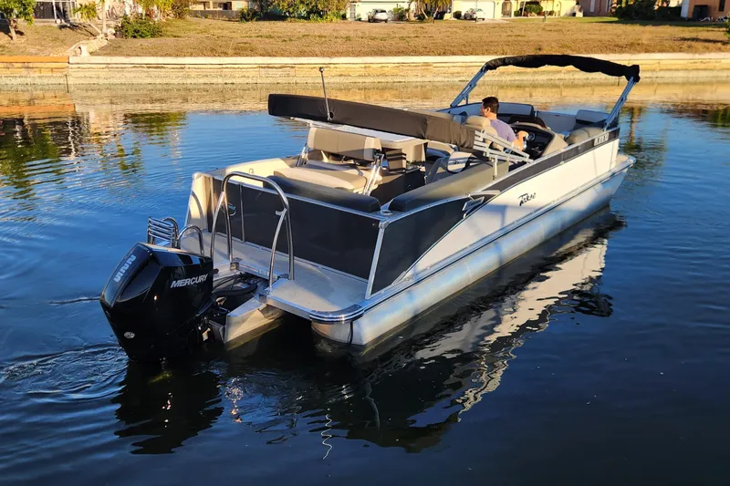 Slide: The Image of 2022 Tahoe Tritune 2585 ENT pontoon boat on calm water with Mercury outboard motor. - 8