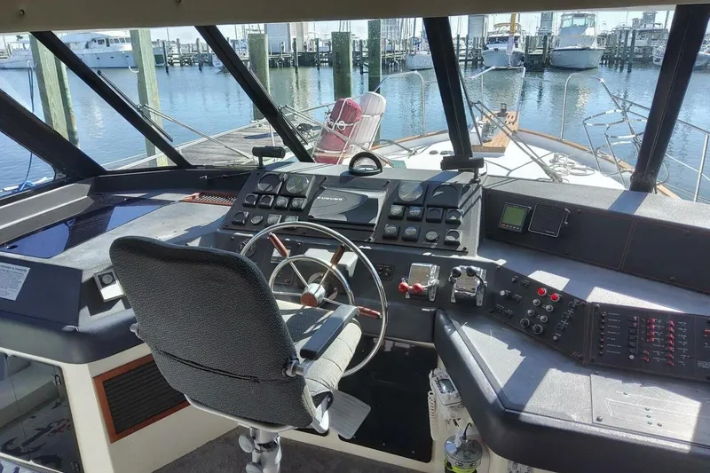 Slide: The Image of 1991 Bayliner 4588 Pilothouse helm with controls, steering wheel, and marina view. - 3