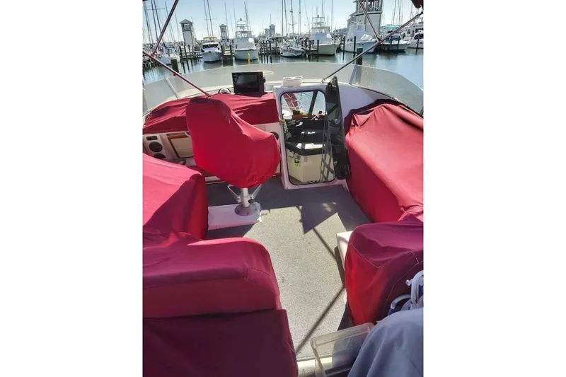 Slide: The Image of 1991 Bayliner 4588 Pilothouse boat interior with red covers, docked at marina. - 4