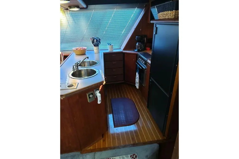 Slide: The Image of 1991 Bayliner 4588 Pilothouse kitchen with dual sinks, stove, and wooden cabinetry. - 7