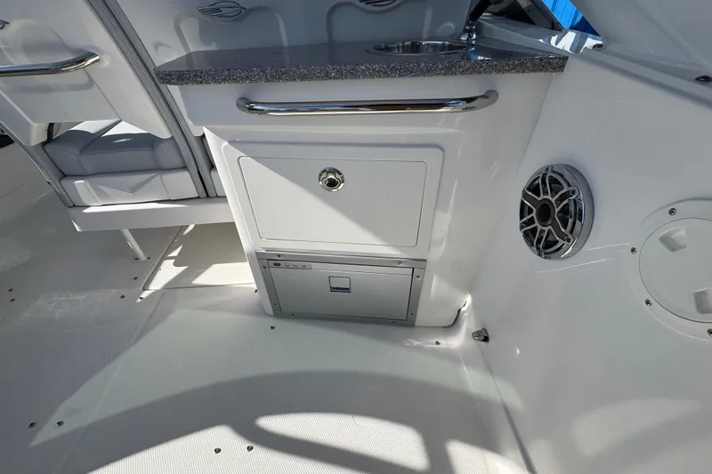 Slide: The Image of Interior of 2026 Chaparral 280 OSX boat featuring a sleek kitchenette and speaker system. - 26