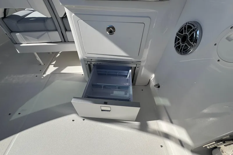 Slide: The Image of 2026 Chaparral 280 OSX boat interior with open storage drawer and speaker. - 28