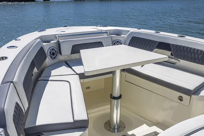 Slide: The Image of Manufacturer Provided Image: 2025 Cobia 265 Center Console boat interior with seating and table on calm water. - 12