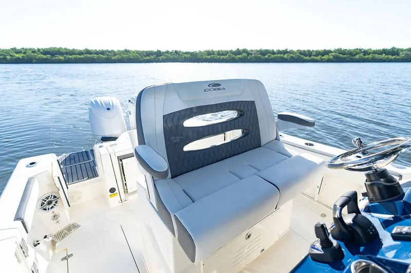 Slide: The Image of Manufacturer Provided Image: 2026 Cobia 245 Center Console boat interior with seating and steering wheel on calm water. - 11