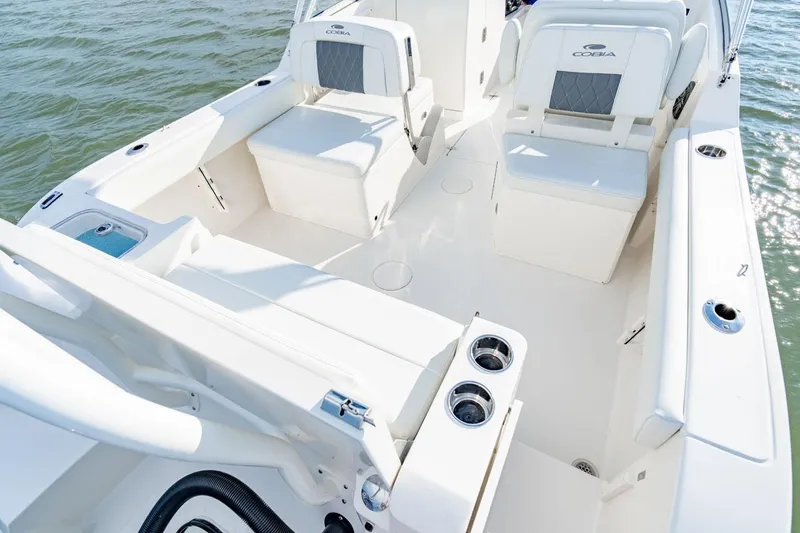 Slide: The Image of Manufacturer Provided Image: 2025 Cobia 220 Dual Console boat interior with seating and cup holders on water. - 10