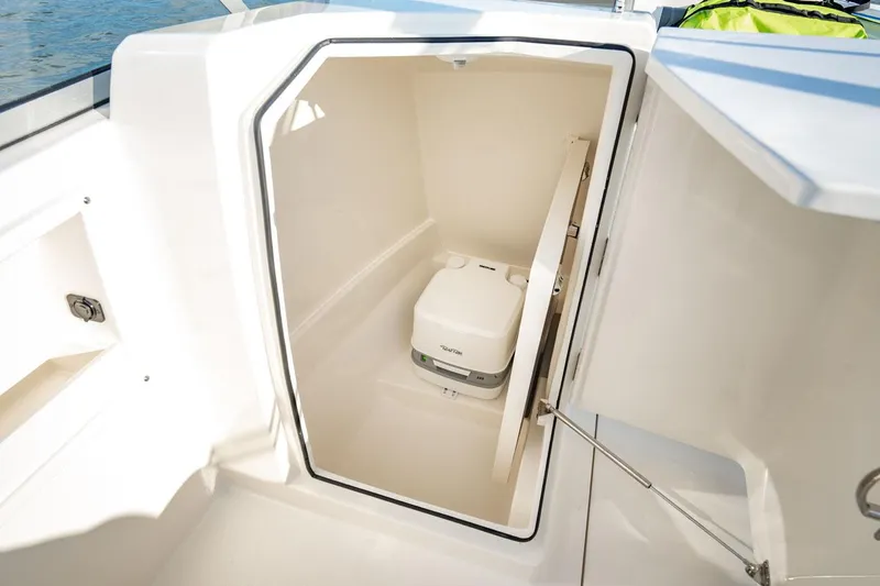 Slide: The Image of Manufacturer Provided Image: 2025 Cobia 220 Dual Console boat interior with compact marine toilet. - 12
