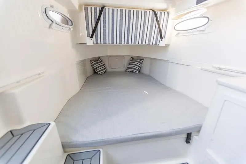 Slide: The Image of Manufacturer Provided Image: 2025 Cobia 350 Center Console cabin interior with striped pillows and portholes. - 21