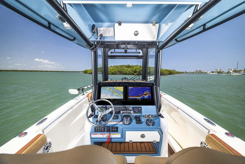 Slide: The Image of Manufacturer Provided Image: 2025 Cobia 265 Center Console Open boat interior with dual navigation screens on calm water. - 12