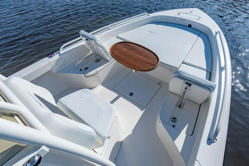 Slide: The Image of Manufacturer Provided Image: 2026 Pathfinder 2600 TRS boat interior with seating and wooden table on calm water. - 6