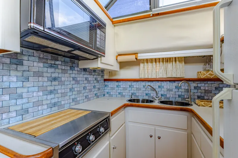 Slide: The Image of Carver 440 yacht kitchen with tiled backsplash, stove, and sink. - 14