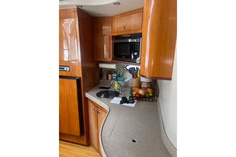 Slide: The Image of 2004 Regal Commodore 3860 yacht kitchen with wooden cabinets, sink, and microwave. - 10