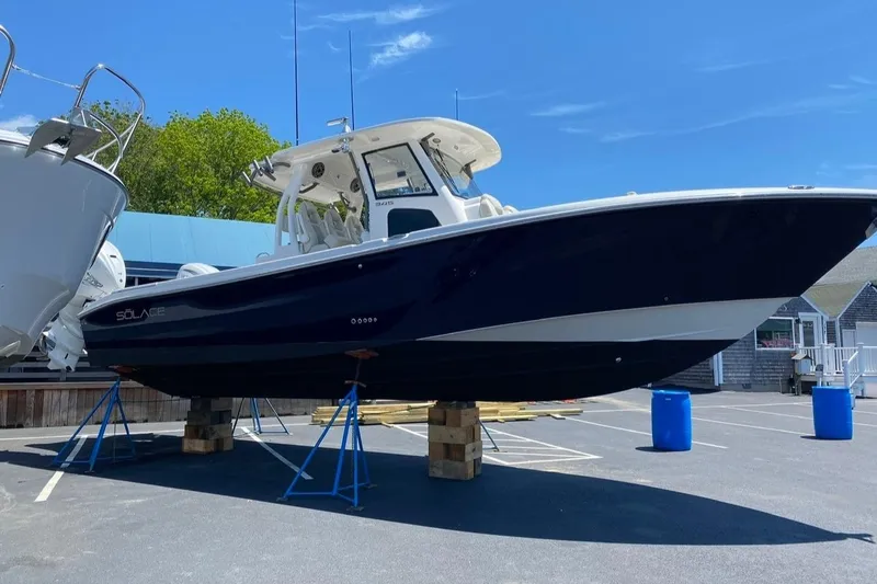 The Image of 2020 Solace 345 boat on stands in a parking lot under clear blue sky. - 0