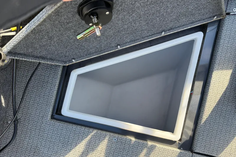Slide: The Image of Open storage compartment in 2022 G3 Angler V17 T boat, featuring gray interior and carpeted lid. - 14