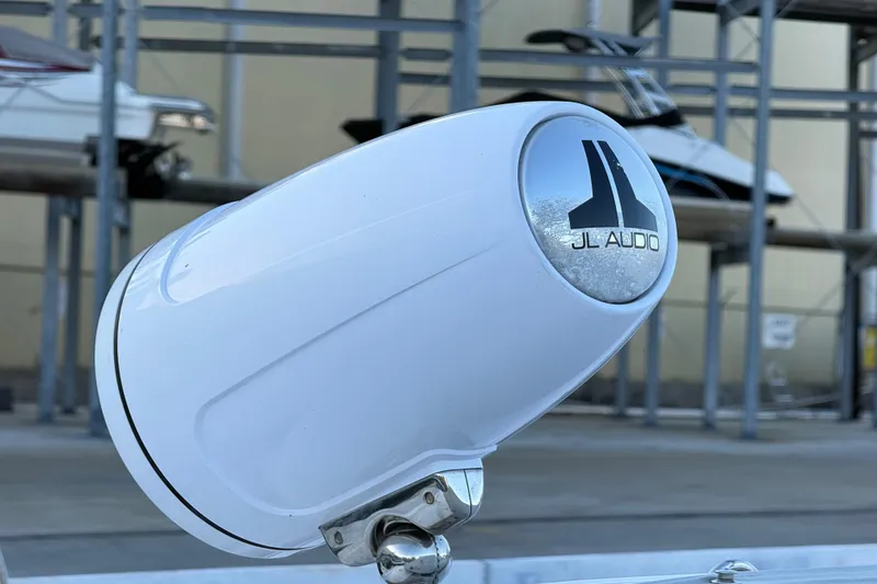 Slide: The Image of White JL Audio speaker on a 2021 Schaefer 303 boat, with docked boats in the background. - 14