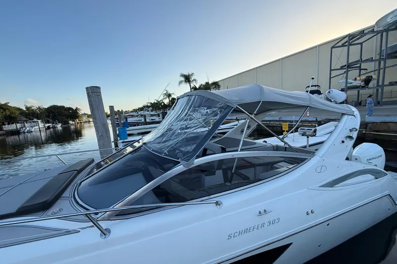 Slide: The Image of 2021 Schaefer 303 boat docked at marina, featuring sleek design and canopy. - 15