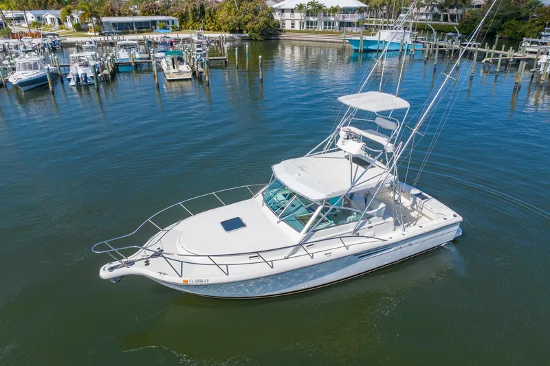 The Image of 1997 Tiara Yachts 3500 Express boat docked in a marina, surrounded by calm waters. - 0