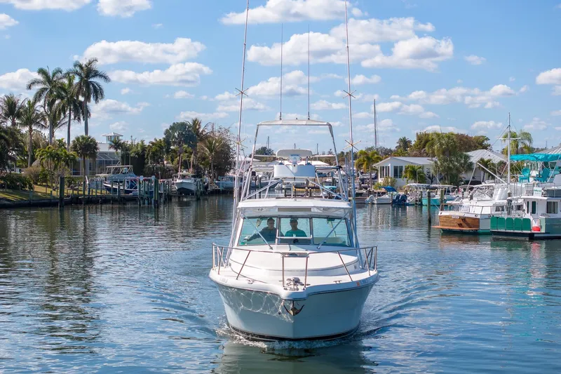 Slide: The Image of 1997 Tiara Yachts 3500 Express cruising in a scenic marina with palm trees. - 10