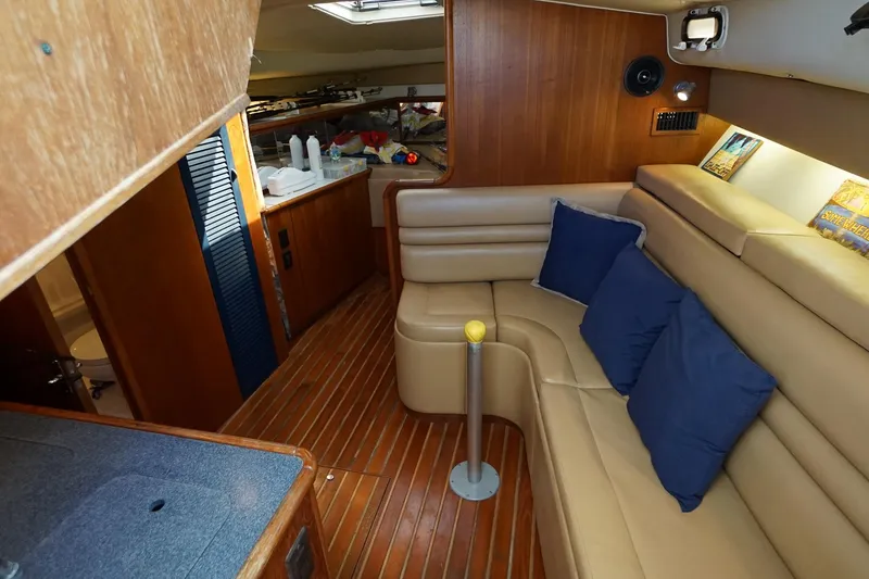 Slide: The Image of 1997 Tiara Yachts 3500 Express interior with beige seating, blue cushions, and wooden accents. - 46