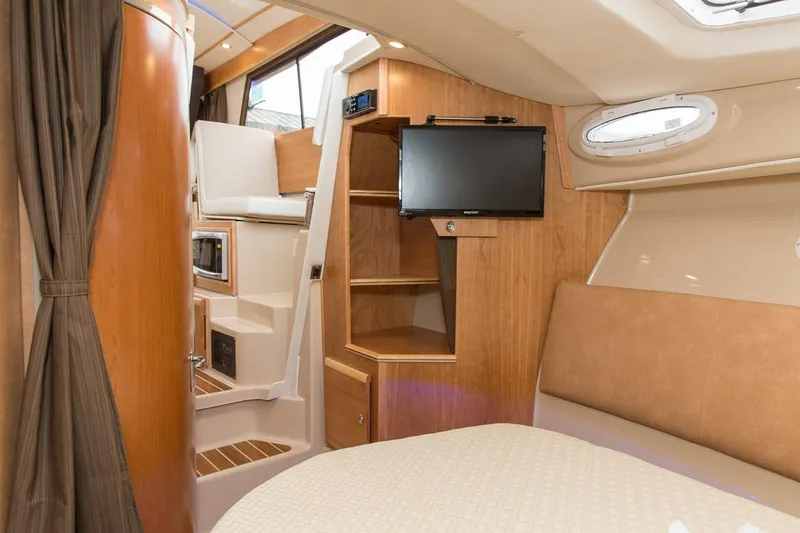 Slide: The Image of Manufacturer Provided Image: Interior of 2022 Cutwater C-30 Sedan boat with TV, wood cabinetry, and seating area. - 11