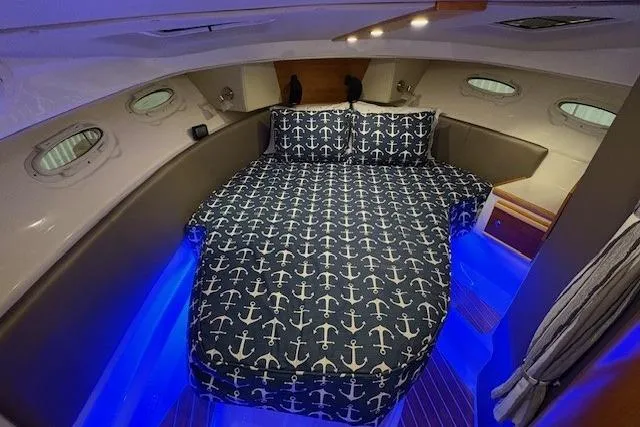 Slide: The Image of 2022 Cutwater C-30 Sedan cabin with anchor-patterned bedding and ambient blue lighting. - 20