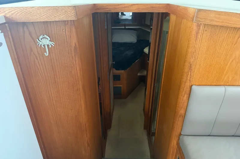 Slide: The Image of 1987 Mainship 36 Nantucket Sedan interior with wooden cabinetry and cozy sleeping area. - 13