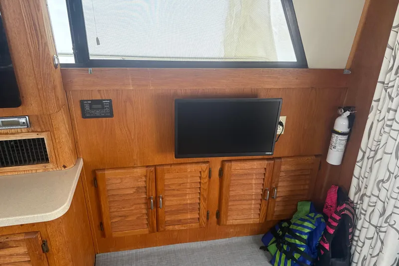 Slide: The Image of 1987 Mainship 36 Nantucket Sedan interior with TV, wooden cabinets, and life jackets. - 14