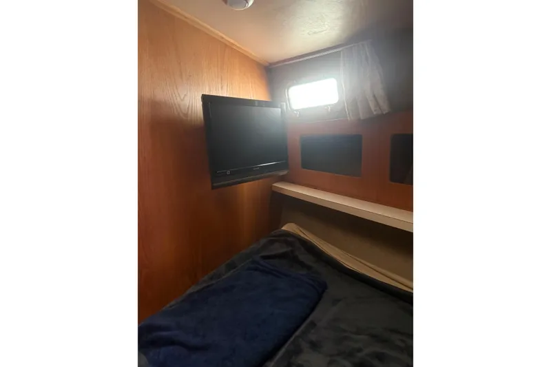 Slide: The Image of 1987 Mainship 36 Nantucket Sedan cabin interior with bed, TV, and window. - 18