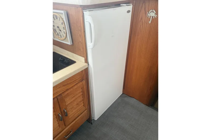 Slide: The Image of 1987 Mainship 36 Nantucket Sedan interior with compact kitchen fridge and wooden cabinetry. - 22