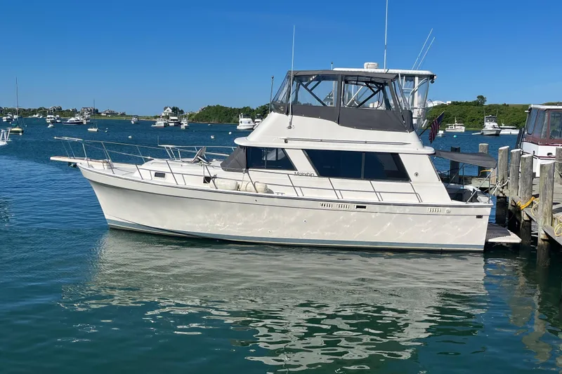 Slide: The Image of 1987 Mainship 36 Nantucket Sedan docked in a scenic marina setting. - 6