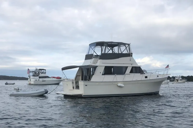 Slide: The Image of 1987 Mainship 36 Nantucket Sedan yacht anchored on calm water under cloudy skies. - 8