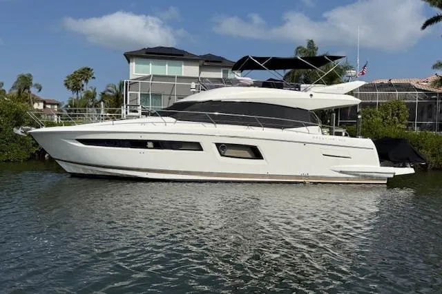The Image of 2015 Prestige 500 yacht docked by waterfront homes under a clear blue sky. - 0
