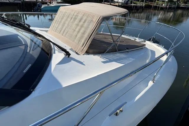 Slide: The Image of 2015 Prestige 500 yacht docked, featuring sleek design and spacious deck, with American flag. - 11