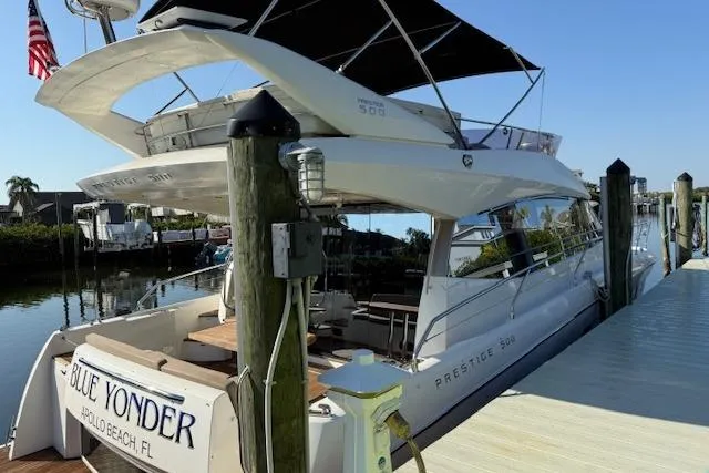 Slide: The Image of 2015 Prestige 500 yacht docked in a marina, surrounded by other boats. - 2