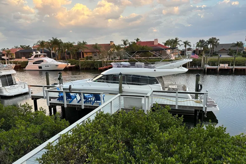 Slide: The Image of 2015 Prestige 500 yacht docked in a marina, surrounded by trees and water. - 3