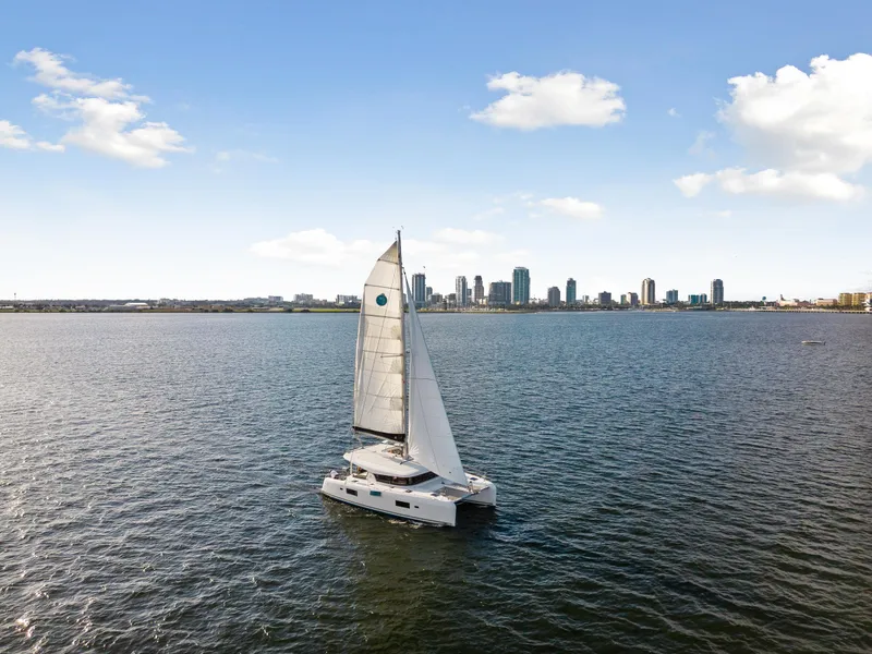 Slide: The Image of Lagoon 42 catamaran sailing on open water with city skyline in the background, 2018 model. - 15