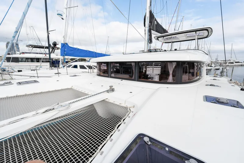 Slide: The Image of 2018 Lagoon 42 catamaran docked at a marina, showcasing its spacious deck and netting. - 40