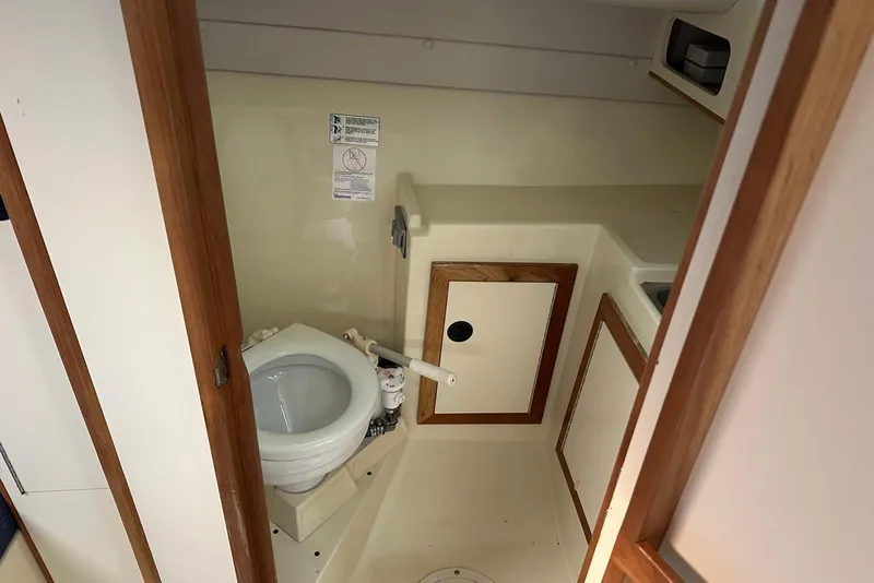 Slide: The Image of 2000 Albin 28 Tournament Express boat bathroom with toilet and wooden accents. - 16
