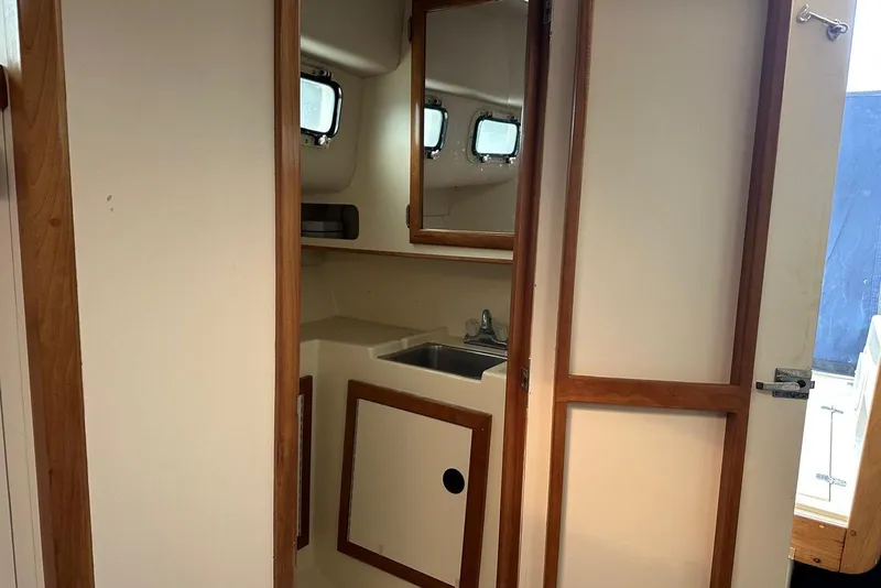 Slide: The Image of Interior of 2000 Albin 28 Tournament Express boat, featuring a compact bathroom with sink and mirror. - 17