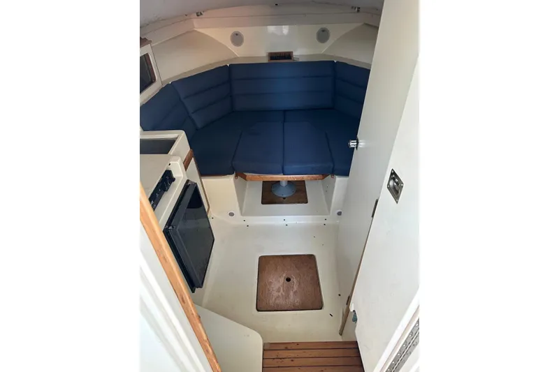 Slide: The Image of Interior of 2000 Albin 28 Tournament Express with blue seating and compact kitchenette. - 25