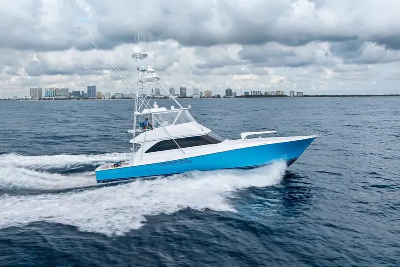 Slide: The Image of 2005 Viking 61 Convertible yacht cruising on open water with city skyline backdrop. - 4